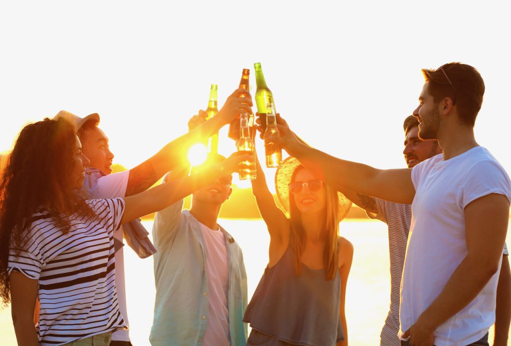 Group of friends hanging out with beer at the beach